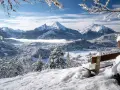 Ein verschneites Tal mit einem majestätischen Berg im Hintergrund. Eine Bank lädt zum Verweilen ein, perfekt für einen **ausflug im winter**.