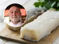 Chef sonriente junto a trozos de bacalao en salazón sobre tabla de madera.