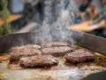 Mehrere saftige Rumpsteaks braten auf einer heißen Platte, Dampf steigt auf.