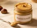 Glas mit Maronencreme, daneben eine Löffelprobe. Perfekt für süße und herzhafte Gerichte – die Maronencreme Verwendung ist vielfältig.