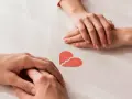Dwie dłonie, symbolizujące 7 etapów akceptacji, nad złamanym sercem.