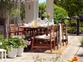 Gemütliche Terrasse mit Holztisch und Stühlen, perfekt, um die Terrasse gestalten mit wenig Geld. Grill und Pflanzen schaffen eine einladende Atmosphäre.