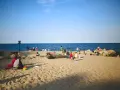 Ludzie odpoczywają na plaży, ciesząc się słońcem i morzem. Widać, ile Szczecin ma do morza – bliskość natury i relaks.