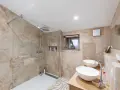 Salle de bain moderne avec douche à l'italienne, double vasque et carrelage en pierre naturelle. Un projet réussi pour refaire la salle de bain.