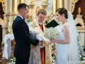Panna młoda w welonie i z bukietem, pan młody w garniturze, podczas ceremonii ślubnej w kościele.