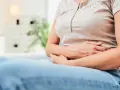 Kobieta trzyma się za brzuch, co może sugerować objawy raka jelita.