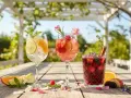 Tre färgglada sangriadrycker med frukt och örter på ett träbord utomhus. Perfekt för ett somrigt sangria recept.