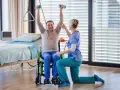 Starszy mężczyzna w wózku ćwiczy z hantlami pod okiem fizjoterapeutki. Czy rehabilitacje można odliczyć od podatku?