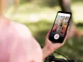 Osoba trzyma telefon z widokiem na ekran Instagrama, gdzie widać siatkę zdjęć i ikonę Reels. Dowiedz się, jak zrobić rolkę na Instagramie ze zdjęć.