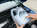 Osoba trzymająca kanister oleju silnikowego TITAN GT1 PRO C-3 SAE 5W-30 nad silnikiem. Czy można mieszać oleje silnikowe? Sprawdź specyfikacje!