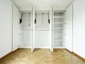 Interno di un armadio bianco a tre ante, vuoto, con ripiani e barre appendiabiti. Un esempio di come costruire un armadio funzionale.