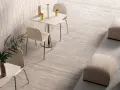 Un caffè moderno con tavolini, sedie e pouf, su eleganti pavimenti senza fughe effetto pietra.