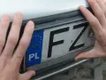 Dwie dłonie trzymają polską tablicę rejestracyjną z literami FZ.