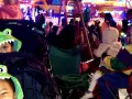 Two kids in dinosaur hoodies watch a vibrant Mardi Gras parade. They're ready for fun at this family-friendly event.