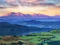 Tatry o zachodzie słońca, jedno z **10 najpiękniejszych miejsc w Polsce**. Góry w odcieniach różu i fioletu, zielone wzgórza i lasy.