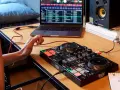 Osoba uczy się, jak zostać DJ-em, ćwicząc na kontrolerze DJ-skim i laptopie z oprogramowaniem muzycznym.