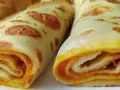 Dwa zwinięte naleśniki z dżemem, apetycznie wyglądające, z widocznym pomarańczowym nadzieniem.