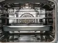 Interior de un horno con rejillas y bandejas, mostrando el ventilador.