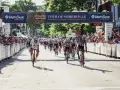 Cyclists race towards the finish line at the Tour of Somerville, America's longest-running bike race, with cheering crowds lining the street.