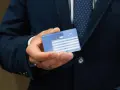 Mężczyzna w garniturze trzyma w dłoni kartę EKUZ Legnica.