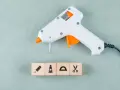 Pistolet do kleju na gorąco i kostki z symbolami: ołówek, farba, linijka, nożyczki. Idealne do kreatywnych projektów, co można kleić klejem na gorąco.