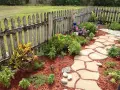 Natürliche Steinplatten formen einen geschwungenen Gartenweg, umgeben von bunten Blumen und grünen Pflanzen. Tolle Gartenweg Ideen für ein idyllisches Zuhause.