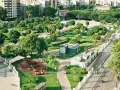 Park z placem zabaw i alejkami, otoczony budynkami. Wygląda jak jeden z najbardziej zielonych miast w Polsce.