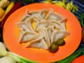 Pyszne pierogi meksykańskie, ułożone na pomarańczowym talerzu, z dodatkiem jalapeño i sosu.
