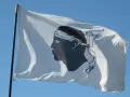 Flaga Korsyki powiewa na wietrze na tle błękitnego nieba.