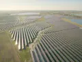 Ogromne połacie paneli fotowoltaicznych tworzą największą farmę fotowoltaiczną w Polsce, rozciągającą się wzdłuż jeziora.