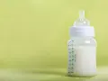 Gotowa do karmienia butelka do karmienia noworodka z mlekiem, na zielonym tle.