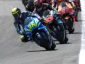 Pilotos de **MotoGP hoy** compiten en una carrera emocionante. El piloto con el número 36 en su Suzuki lidera, inclinado en una curva cerrada.