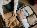 Pakowanie walizki. Zastanawiasz się, ile kosztuje dokupienie bagażu rejestrowanego Ryanair? W środku ubrania, torebka i kosmetyki.