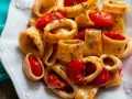 Un piatto invitante di pasta calamarata con pomodorini freschi e prezzemolo tritato, pronto per essere gustato.