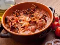 Polipetti in purgatorio, un piatto succulento con tentacoli che danzano in un sugo rosso, accompagnati da pomodorini freschi e cipolla.