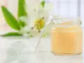 Un vasetto di pappa reale, con un fiore sullo sfondo. Alcuni credono che la pappa reale fa ingrassare, ma è un alimento nutriente.