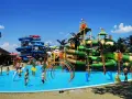 Wodne szaleństwo w jednym z najlepszych aquaparków w Europie! Dzieci pluskają się w basenie, a w tle widać imponujące zjeżdżalnie i tropikalną roślinność.