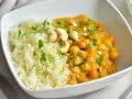 Curry de garbanzos cremoso con arroz blanco y anacardos en un cuenco blanco.