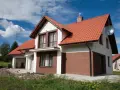 Jaki kolor elewacji do czerwonego dachu? Biała elewacja z brązowymi akcentami, jak na tym domu, wygląda stylowo.