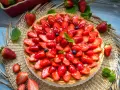 Ein leckerer Erdbeerkuchen mit einem wunderschönen Muster aus frischen Erdbeeren und Blaubeeren, glasiert und garniert mit Minze.