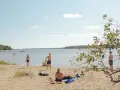 Solig dag vid Hallmare havsbad. Människor njuter på stranden, badar och leker i vattnet.