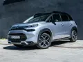 Srebrny Citroen C3 Aircross na tle ciemnej ściany. Wiele osób szuka **Citroen C3 Aircross opinie** przed zakupem.
