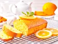 Un soffice plumcake al limone, guarnito con una fetta d'arancia e menta, su una griglia, pronto per essere gustato.