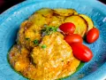 Köttbullar i krämig cafe de paris sås med rostade potatisskivor och körsbärstomater på en blå tallrik.