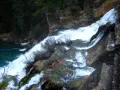 El salto de Poveda, una cascada de agua blanca y espumosa que desciende por rocas y vegetación, desemboca en un río de aguas turquesas.