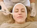Kosmetikerin trägt eine Maske auf, um die Haut zu reinigen.