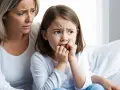 Zmartwiona mama wspiera córkę, która obgryza paznokcie. Problem obgryzania paznokci u dzieci wymaga uwagi psychologa.