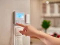 Dito si vede come funziona un termostato manuale: una mano preme un pulsante per regolare la temperatura.