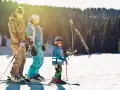 Rodzina na stoku narciarskim, idealnym dla dzieci. Słońce, śnieg i radość z jazdy.