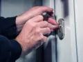 Mains expertes manipulant des outils pour tenter de comment ouvrir un portail sans clé.